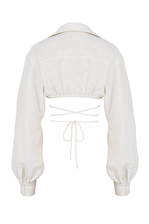 Blouse cropped blanche cassée élégante associée à une mini-jupe taille haute tendance.