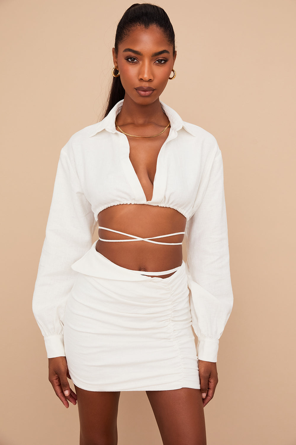 Blouse cropped blanche cassée élégante associée à une mini-jupe taille haute tendance.