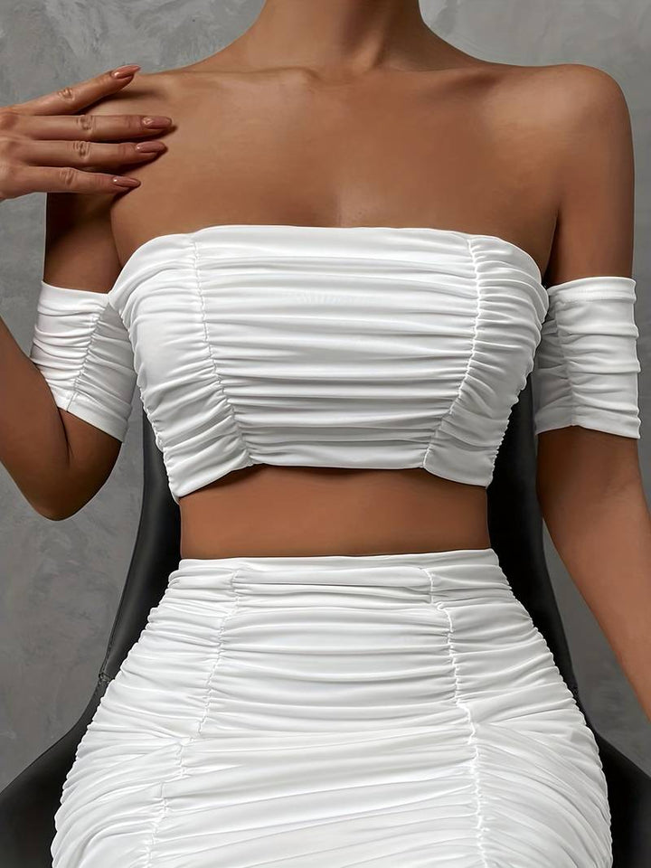 Ensemble chic avec un top à épaules dénudées et des ruchés, accompagné d'une mini-jupe assortie.