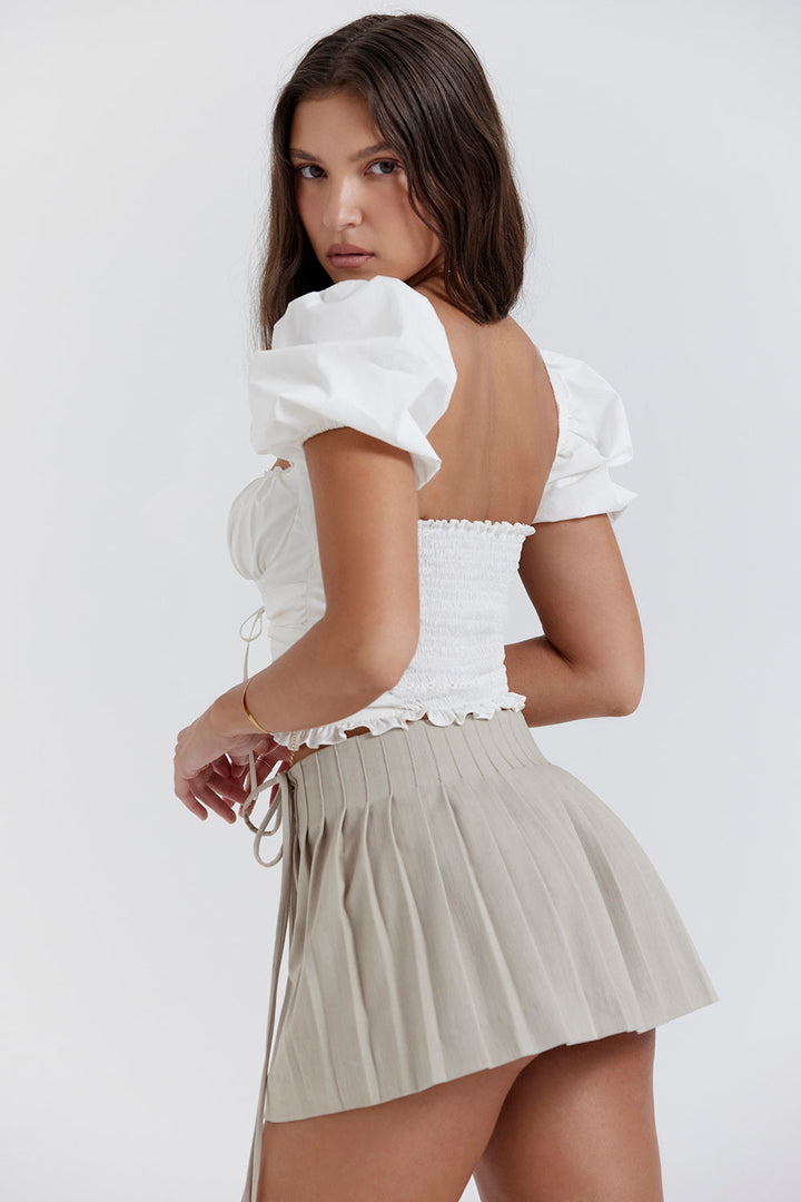 Top court plissé blanc avec mini-jupe portefeuille beige - une tenue estivale élégante pour toutes les occasions.