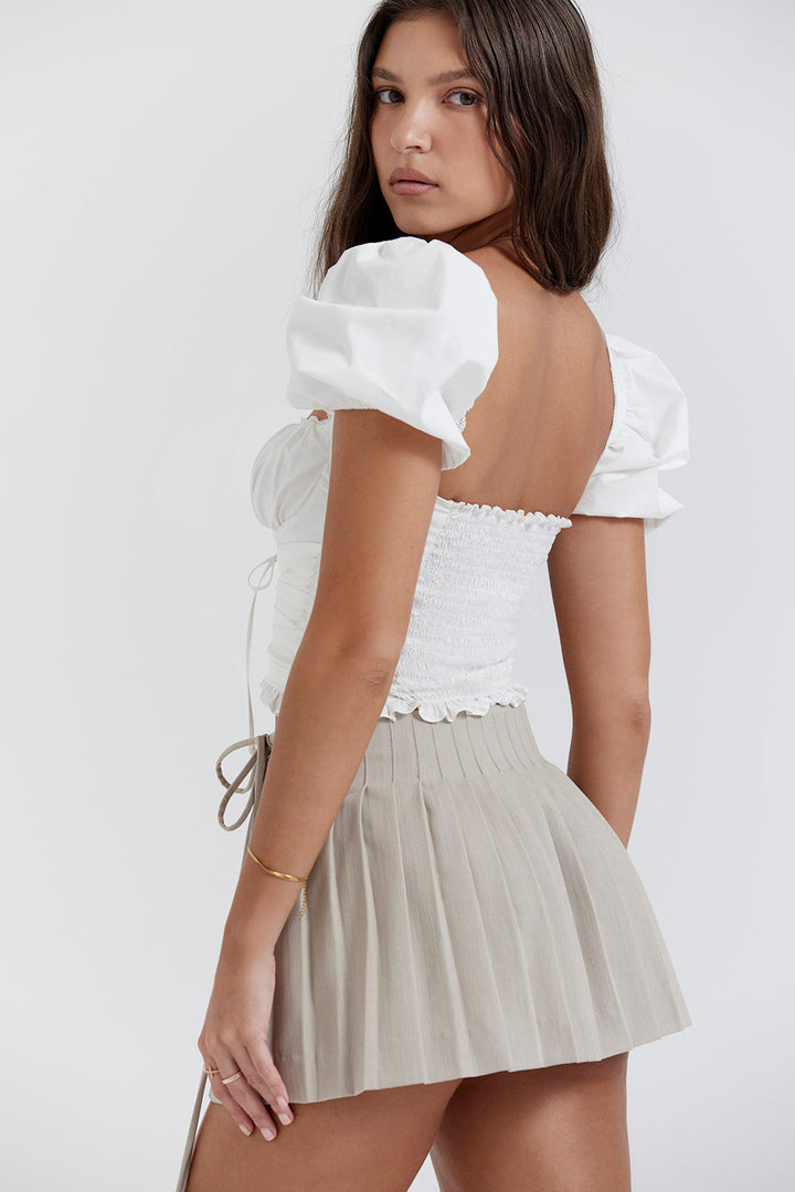 Top court plissé blanc avec mini-jupe portefeuille beige - une tenue estivale élégante pour toutes les occasions.